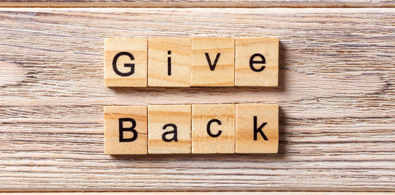 Give Back word written on wood block. Give Back text on table, concept.
