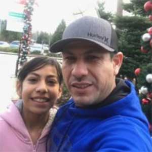 Two people smiling together outdoors near holiday decorations