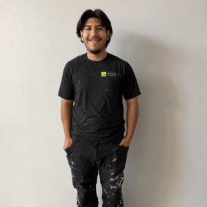 Smiling worker in a black Morgan shirt and paint-marked work pants